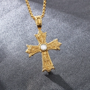 Détail macro du pendentif croix dorée gothique aux textures complexes et gemme centrale