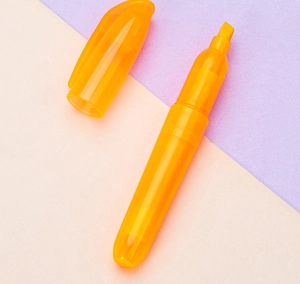 Detailansicht der orangenen Textmarker-Spitze auf pastellfarbenem Hintergrund