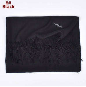 Detail of soft black cashmere scarf featuring fringe trim and brand material label