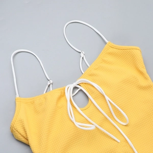 Détail de la maille gaufrée jaune et des brides blanches nouées sur cette robe d'été