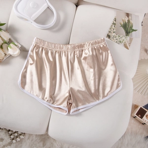 Close-up of champagne satin shorts with white piping on a cozy cream sofa background