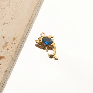 Macro shot of 18K gold dolphin pendant with blue crystal gemstone on a reflective surface