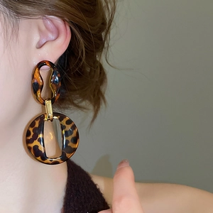 Close-up of leopard print acrylic drop earrings worn by a model in a fashion style
