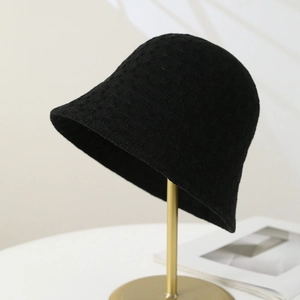 Dettaglio del cappello alla pescatora nero in maglia con trama traforata su supporto