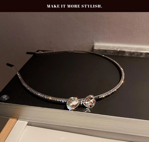 Detail of silver bow headband with sparkling rhinestones on a dark surface
