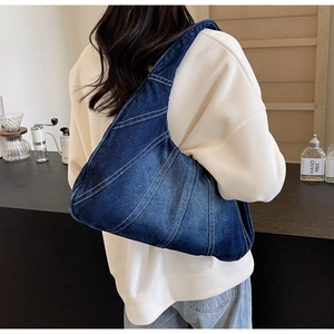 Détail du sac bandoulière en denim bleu avec surpiqûres décoratives et forme de croissant