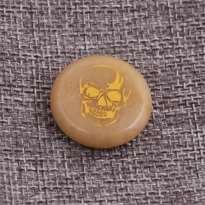 Detailed view of hand-carved golden skull on polished yellow stone round pendant