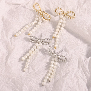 Detailed view of bow knot earrings with pearls in gold and silver finishes