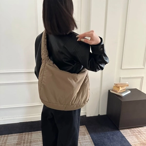 Khaki quilted shoulder bag shown on model's shoulder against a minimalist background