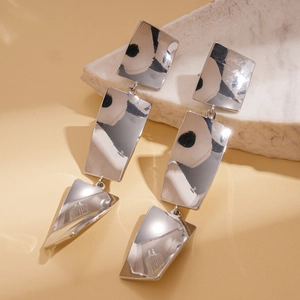Macro view of silver geometric layered earrings with polished mirror finish on stone