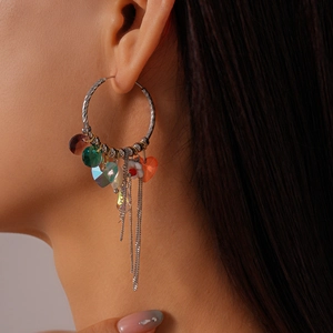 Detail of silver hoop earrings with heart-shaped crystals and long chain tassels on model
