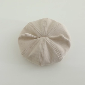 Close-up of beige knitted beret showing detailed ribbed texture and octagonal stitching