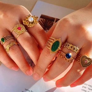 Retro gold-finish rings with colorful gemstones and pearls on model hands
