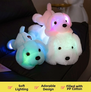 Close-up of three glowing plush puppies in pink blue and white on a dark sofa