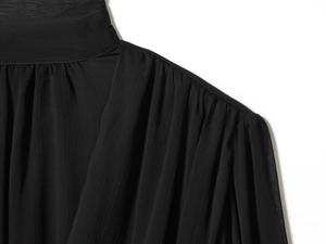 Primer plano detallado de las mangas abullonadas plisadas de una blusa de gasa negra