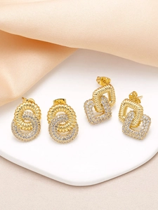 Detail of gold-plated crossover earrings set with sparkling zircon pavé on silk fabric