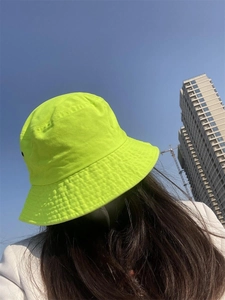 Detail of neon green cotton bucket hat with sun protection for women in outdoor sunlight