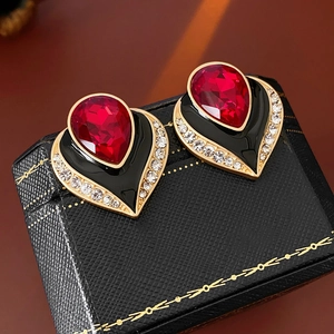 Macro view of vintage heart earrings with red gemstone and black enamel in a jewelry box