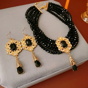 Detail of vintage multi-layer black beaded necklace and matching drop earrings on grey velvet