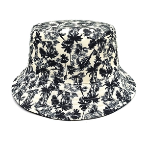 Detail view of the tropical palm tree print on a beige canvas bucket hat surface