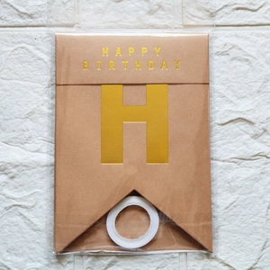 Close-up of brown kraft paper fishtail banner with gold foil Happy Birthday lettering