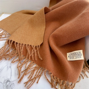 Detail of camel and caramel cashmere scarf showing soft texture and tassel edges
