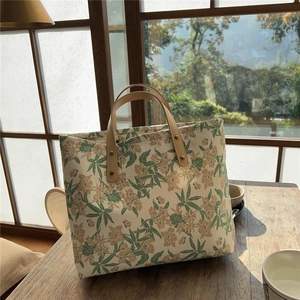 Close-up of floral cotton tote bag with leather handles on a rustic wooden table
