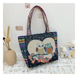 Close-up of owl embroidery on blue canvas tote bag with woven ethnic style strap