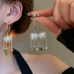 Macro shot of silver tassel earrings with pearls and star charms on a model