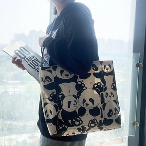 Close-up of a panda print canvas tote bag carried over the shoulder by a model