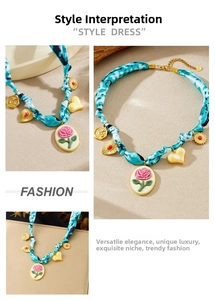 Close-up of vintage gold plated oval cameo and heart charms on a blue fabric chain
