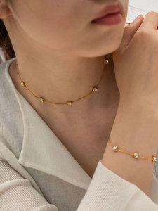 Close-up of gold titanium steel jewelry set featuring blue zircon inlays on necklace and bracelet