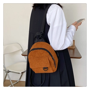 Detailed close-up of a vintage brown corduroy mini backpack with front snap pocket