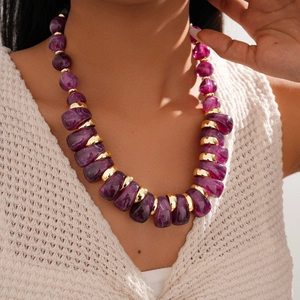 Macro detail of chunky purple acrylic beads and gold metal spacers on adjustable necklace