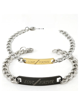 Detail of couple bracelets with gold and black plates engraved with LOVE FOREVER text