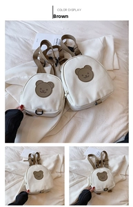 Detail of white canvas kids backpack featuring brown bear patch and adjustable straps