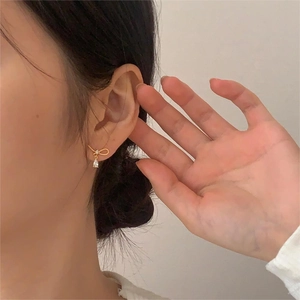 Detailed close-up of a golden bow earrings with sparkling teardrop-shaped zircon stones