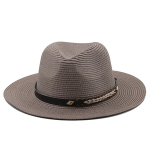 Detail of a dark brown straw fedora hat featuring a black leather band and metal buckle