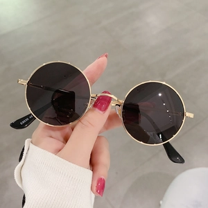 Detail view of round vintage polarized sunglasses with gold metal frame and dark lenses