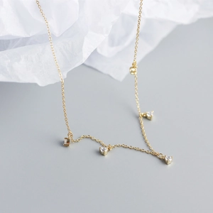 Close-up of a delicate gold s925 silver necklace featuring small sparkling crystal charms