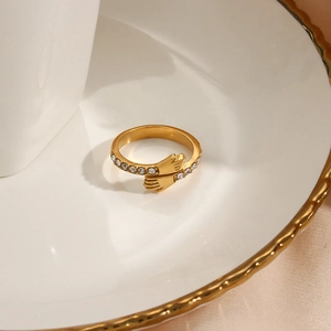 Macro detail of gold hug ring with zircon accents on a white ceramic plate