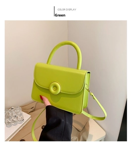 Close-up of a lime green leather handbag featuring a round decorative buckle and shoulder strap