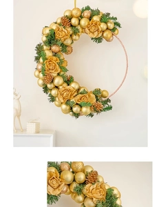 Detail of a gold Christmas wreath with pine cones and roses on a white wall