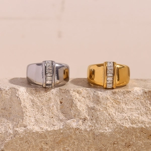 Detail of gold and silver thick bands with rectangular baguette zirconia on raw stone