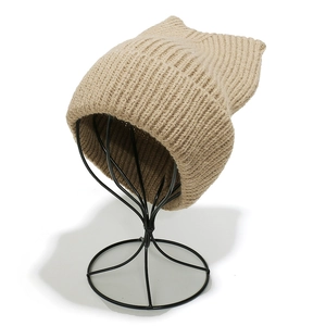 Close-up of oatmeal knit cat ear beanie with thick vertical ribbed texture on a stand