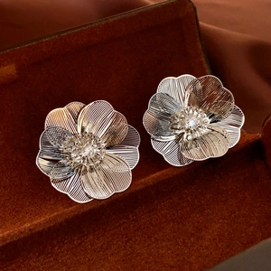 Macro shot of silver hollow-out flower earrings with detailed metallic textures