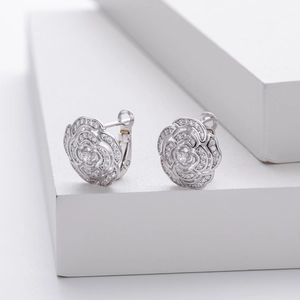 Macro detail of silver rose stud earrings with micro-set zircons on geometric blocks