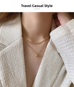 Détail d'un collier double rang doré à perles porté sur un blazer blanc texturé