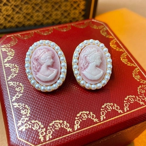 Macro view of vintage cameo earrings with white pearls and gold trim on jewelry box