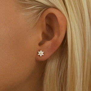 Close-up of a floral gold earring with clear zircons worn on a model's cartilage